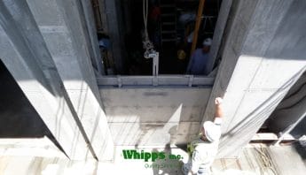 Photo of stainless steel stop logs being installed by a lifter from Whipps, Inc.