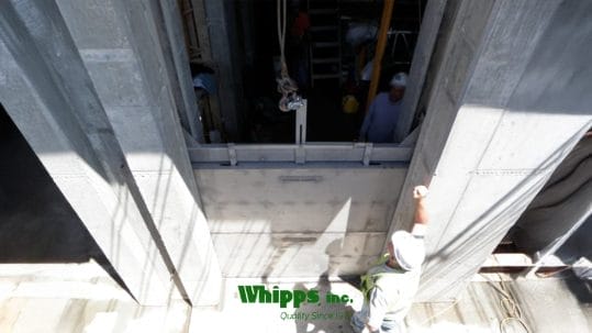 Photo of stainless steel stop logs being installed by a lifter from Whipps, Inc.