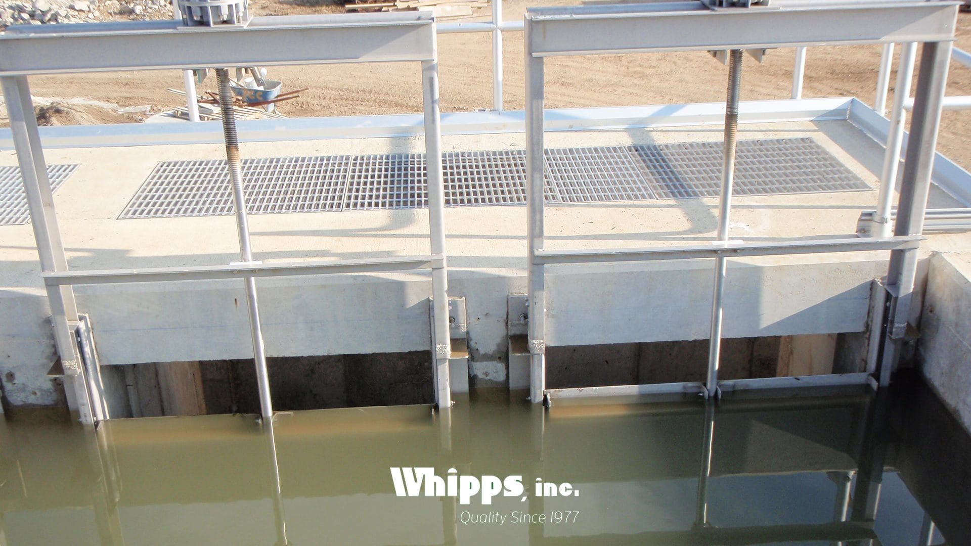 Stainless steel slide gate installed in a concrete channel at an Ohio wastewater treatment plant, submerged in turbulent water with visible foam and debris.